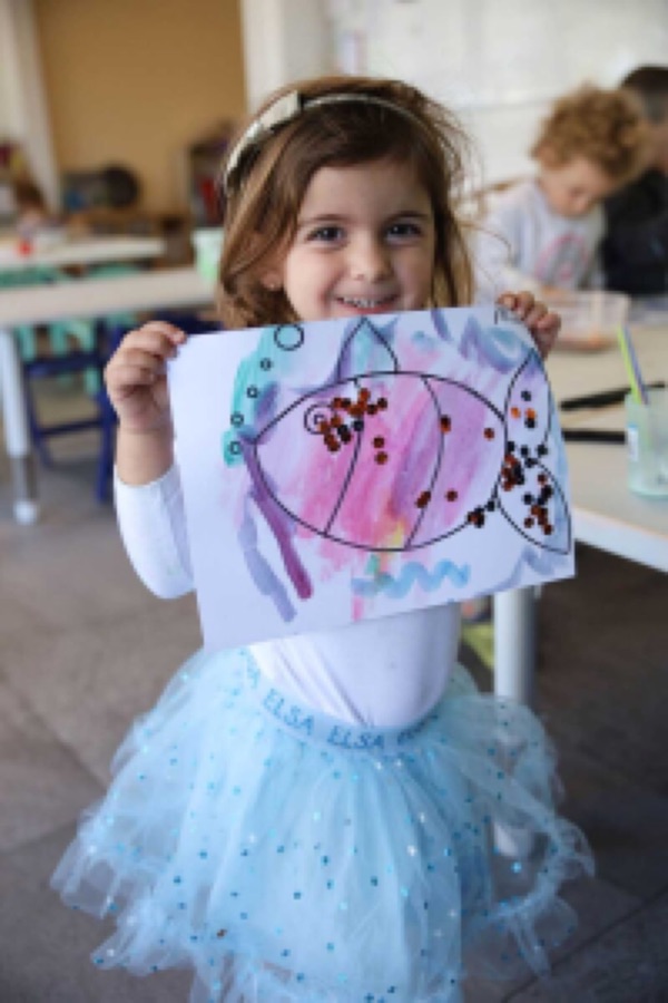 Child proudly showing off a piece of artwork made during a ColorBloom incursion