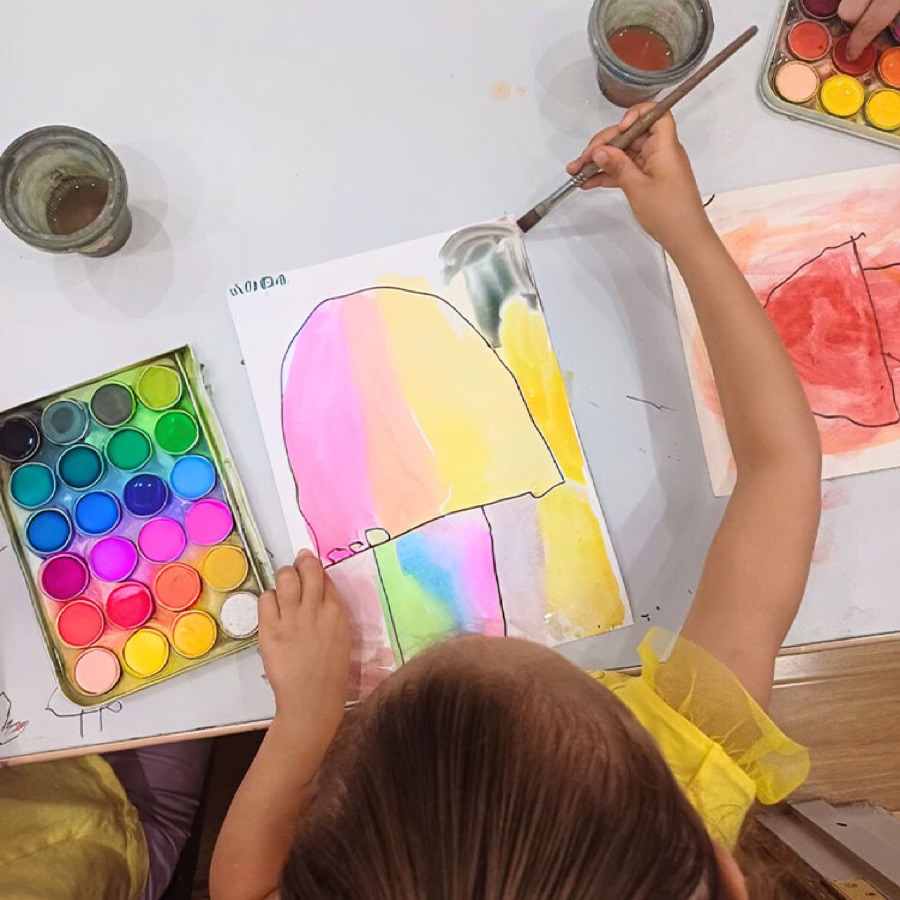 Child painting a colourful watercolour artwork at a ColorBloom workshop